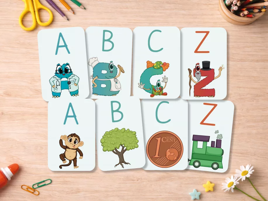 Alphabetkarten A–Z mit Aloni-Buchstaben als Charaktere, Tieren und Gegenständen aus der Lebenswelt, ausgelegt auf einem Holztisch – Lernmaterial für Kindergarten und Vorschule.